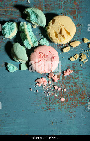 Bright tasty broken macaroons cakes on old wooden background Stock Photo
