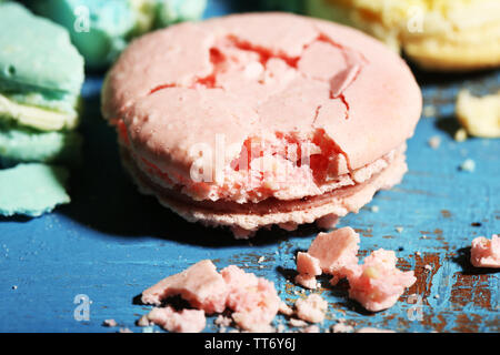 Bright tasty broken macaroons cakes on old wooden background Stock Photo
