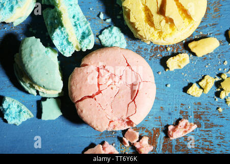 Bright tasty broken macaroons cakes on old wooden background Stock Photo