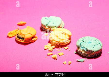 Bright tasty broken macaroons cakes on pink background Stock Photo