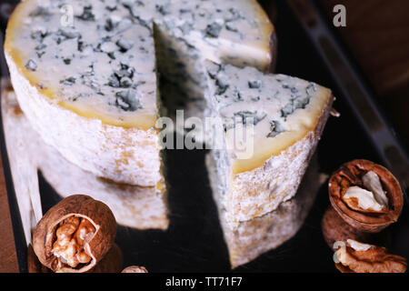 Blue cheese with nuts on metal tray and wooden table background Stock Photo