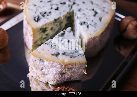 Blue cheese with nuts on metal tray and wooden table background Stock Photo