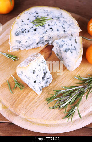 Blue cheese with sprigs of rosemary and oranges on board and wooden table background Stock Photo