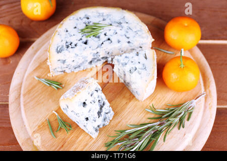 Blue cheese with sprigs of rosemary and oranges on board and wooden table background Stock Photo