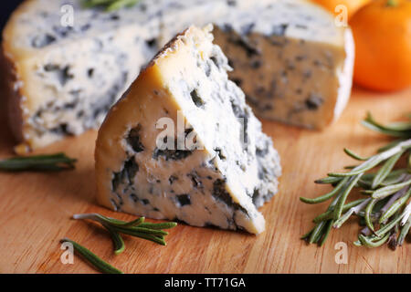 Blue cheese with sprigs of rosemary and oranges on wooden board background Stock Photo