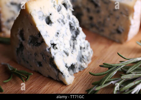 Blue cheese with sprigs of rosemary on wooden board background Stock Photo