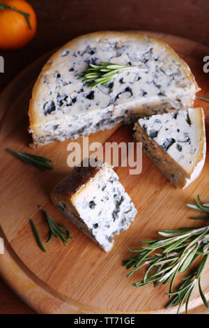 Blue cheese with sprigs of rosemary and orange on wooden board background Stock Photo