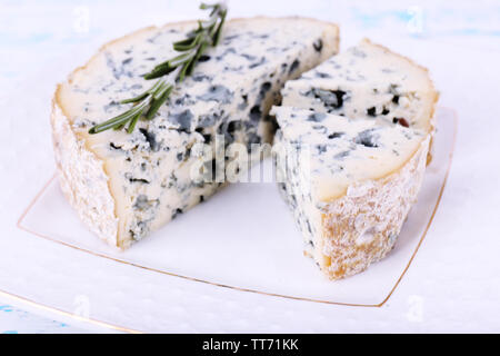 Blue cheese with sprigs of rosemary on plate and color wooden table background Stock Photo