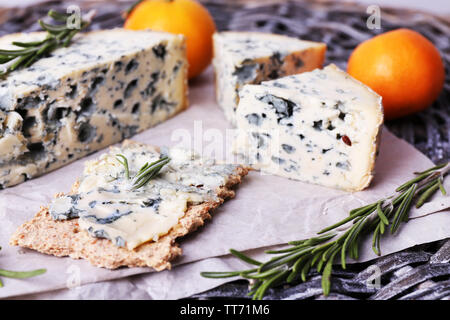 Blue cheese with sprigs of rosemary and oranges on wicker mat background Stock Photo