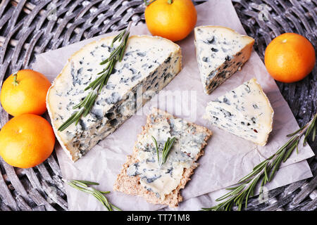 Blue cheese with sprigs of rosemary and oranges on wicker mat background Stock Photo