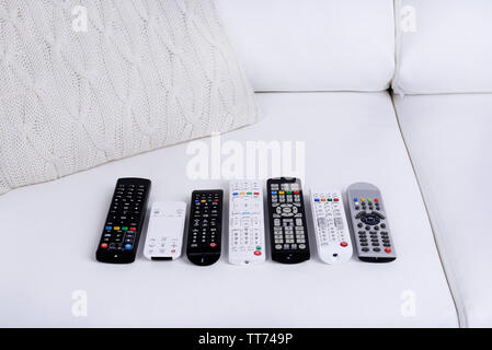 Many remote control devices on sofa Stock Photo