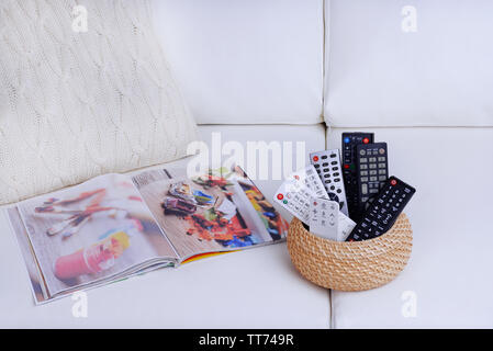 Many remote control devices on sofa Stock Photo