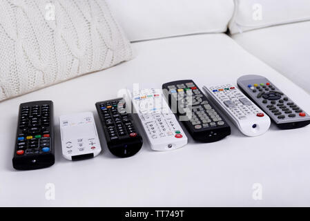 Many remote control devices on sofa Stock Photo