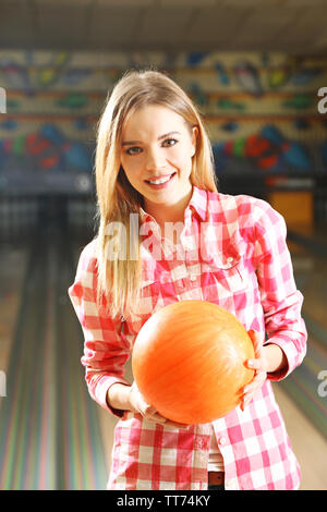 Young woman holding bowling ball in club Stock Photo