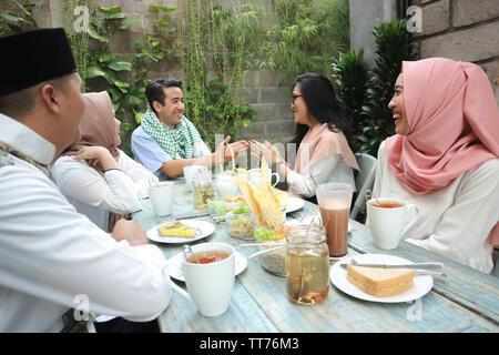 Group happy young muslim embracing each others in dining table during ramadan celebration Stock Photo