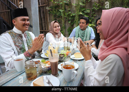 Group happy young muslim embracing each others in dining table during ramadan celebration Stock Photo