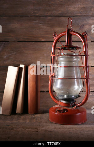 Kerosene lamp with books on rustic wooden background Stock Photo
