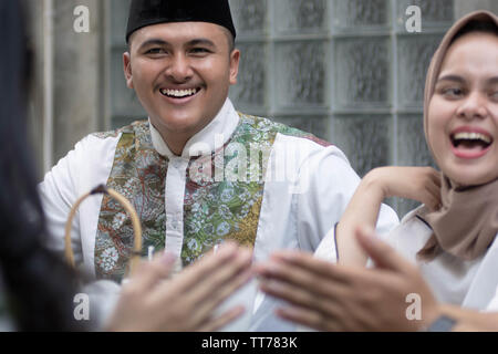 muslim man and woman smile and laughing while having greeting at dining table  during lunch and diner during ramadan celebration, break fasting Stock Photo