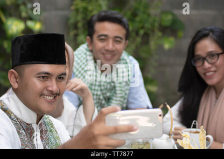 group of muslim taking selfie and smiling while having lunch during ramadan celebration, break fasting Stock Photo