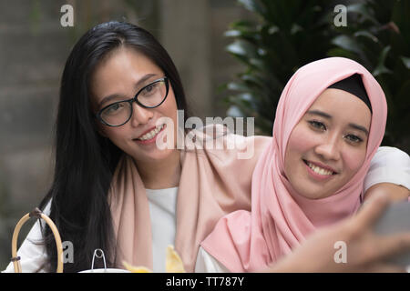 two beautifull asian women looking at camera while hugging each other Stock Photo