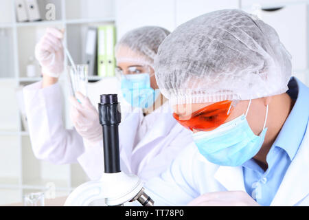 Male and female scientists using microscope in laboratory Stock Photo
