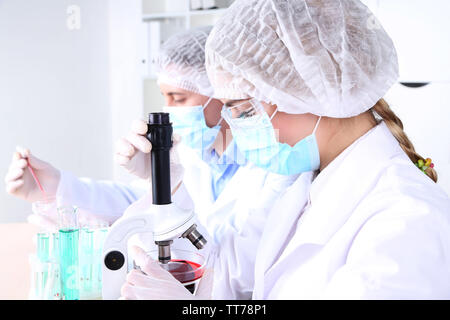 Male and female scientists using microscope in laboratory Stock Photo