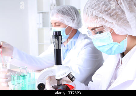 Male and female scientists using microscope in laboratory Stock Photo
