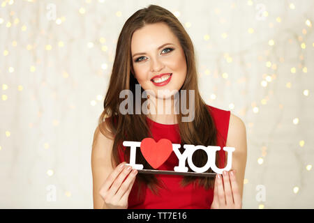 Smiling girl  holding decorative wooden inscription on lights background Stock Photo