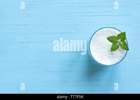 Yogurt drink (ayran, kefir, lassi) in glass - healthy summer refreshing cold drink on blue, copy space. Stock Photo