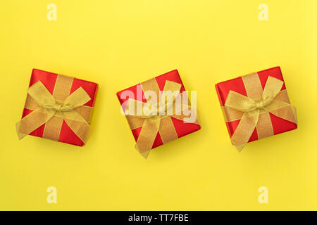 Three Gift boxes with golden bows on yellow background. Top view. Stock Photo