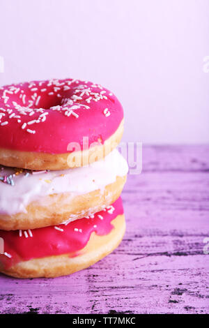 Delicious donuts with icing on table on light background Stock Photo