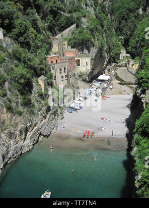 BEACH IN A GORGE IN AMALFI WITH TOURISTS BATHING, BOATING AND RELAXING ON BEACH,  AMALFI,  ITALY. Stock Photo