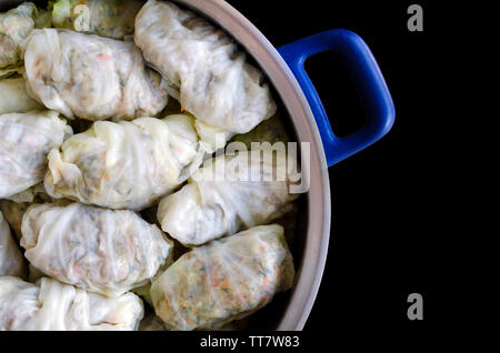 Cabbage Rolls or Dolma. Stuffed cabbage leaves with minced meat, rice, vegetables and herbs in casserole. Isolated on black backround with copy space Stock Photo