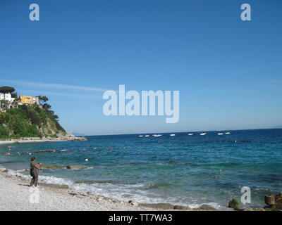 A TOURIST TAKING PHOTOGRAPHS OF BOATS OFF CAPRI ISLAND WITH  THE MEDITTARREANEAN SEA IN THE BACKGROUND,  ITALY. Stock Photo