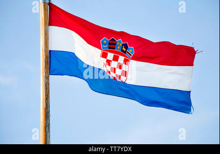 Croatian national flag fluttering on wooden pole against the blue sky Stock Photo