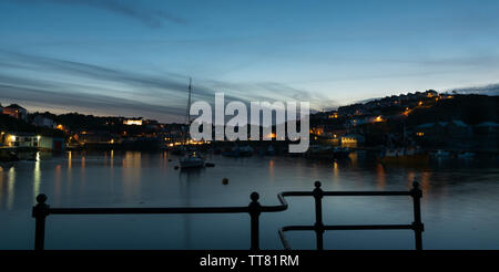 Mevagissey harbour at night with building lights reflected on water. Stock Photo