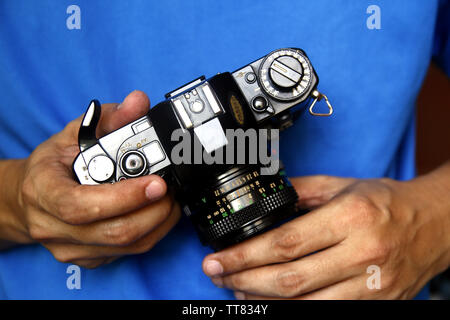 Close up photo of a pair of a man’s hands holding a 35mm manual film camera Stock Photo