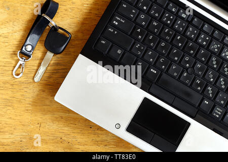 Photo of a laptop computer and car key on a table inside a bedroom Stock Photo