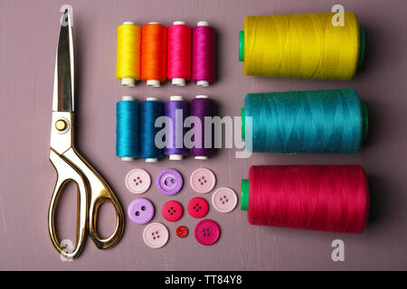 Multicolor sewing threads with buttons and scissors on wooden background Stock Photo