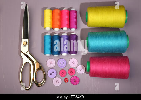 Multicolor sewing threads with buttons and scissors on wooden background Stock Photo
