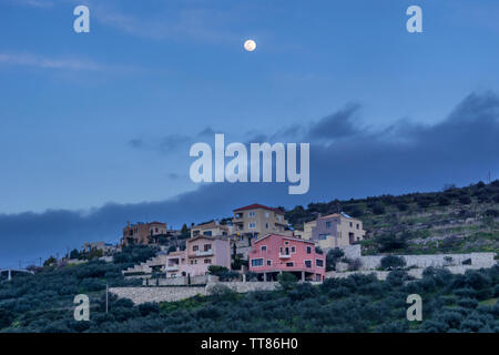 Archanes, Crete Island / Greece. Full moon above Archanes village in the perfecture of Heraklion at late afternoon time Stock Photo
