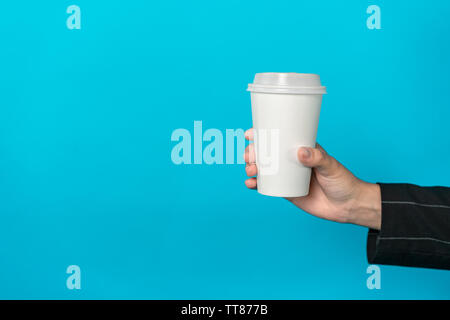Cup of coffee in female hand with light blue background. Woman hold a cup with the drink