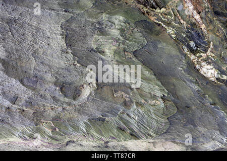Textured surface of natural rock, where you can see layers of rock and white crystals formed over time. Can be used as wallpaper. Stock Photo