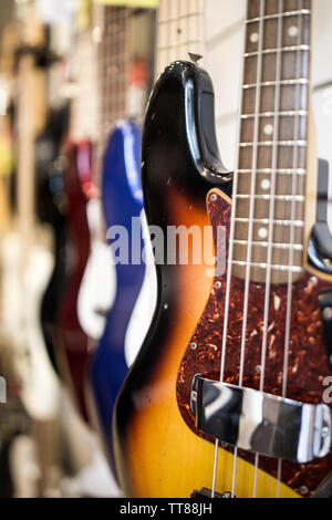 bass guitars hanging on the wall of music store on sale Stock Photo