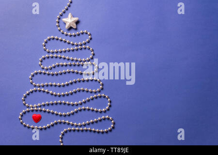 Simple christmas tree concept with silver bead chain, brocade star and red heart on dark blue background - text space Stock Photo
