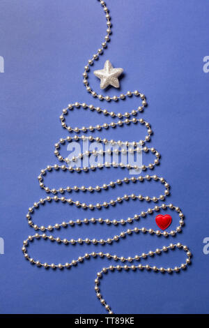 Simple christmas tree concept with silver bead chain, brocade star and red heart on dark blue background Stock Photo