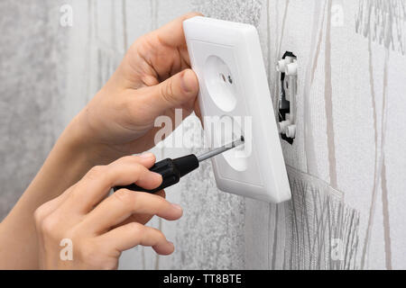 hands of an electrician installing a wall power socket with screwdriver Stock Photo