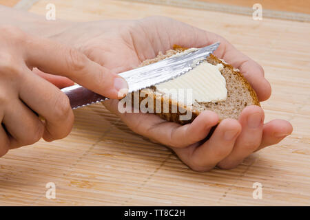 woman hands spreading butter on piece of rye bread, closeup Stock Photo