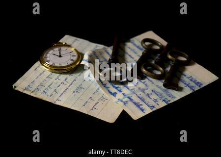 ancient keys and pocket clock on a handwritten letters Stock Photo