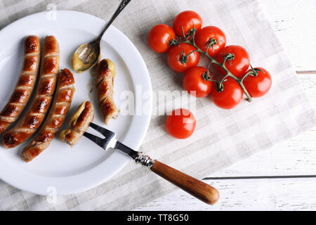 Grilled sausages on plate and cherry tomatoes on table close up Stock Photo